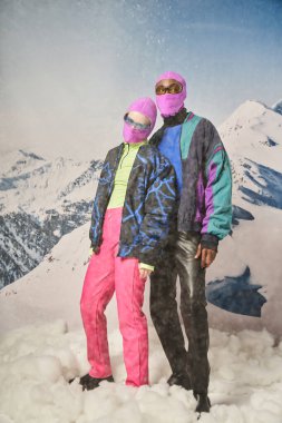 Pembe kar maskeleriyle poz veren çekici çift. Dağ manzaralı, kış konsepti.