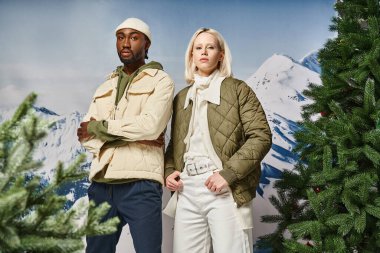 stylish african american with crossed arms posing next to his voguish girlfriend, winter fashion clipart