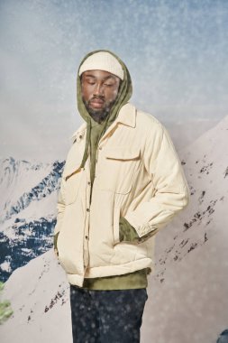 Kış kıyafetleri içinde şık bir adam kar altında elleri ceplerinde, moda ve tarz sahibi.