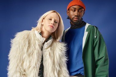 Kışın arka planda dağla poz veren çok ırklı çift, Afro-Amerikan erkek ve kadın.