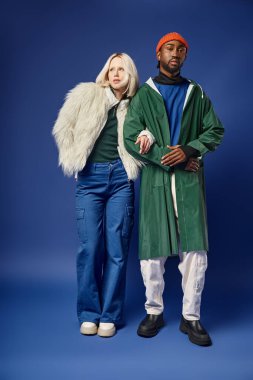 Kışın arka planda dağla poz veren çok ırklı çift, Afro-Amerikan erkek ve kadın.