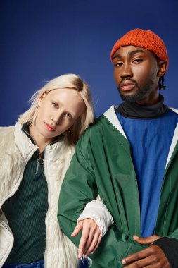 Kışın arka planda dağla poz veren çok ırklı çift, Afro-Amerikan erkek ve kadın.