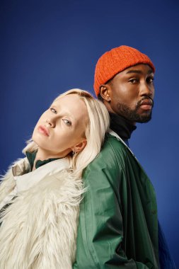 Kışın arka planda dağla poz veren çok ırklı çift, Afro-Amerikan erkek ve kadın.