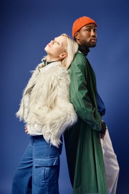 Kışın arka planda dağla poz veren çok ırklı çift, Afro-Amerikan erkek ve kadın.