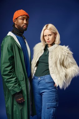 Kışın arka planda dağla poz veren çok ırklı çift, Afro-Amerikan erkek ve kadın.