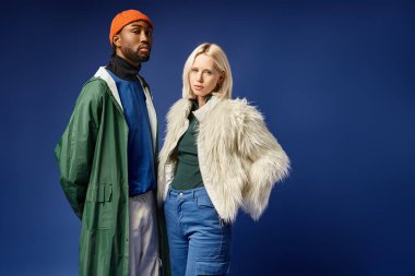 Kışın arka planda dağla poz veren çok ırklı çift, Afro-Amerikan erkek ve kadın.