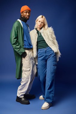 Kışın arka planda dağla poz veren çok ırklı çift, Afro-Amerikan erkek ve kadın.