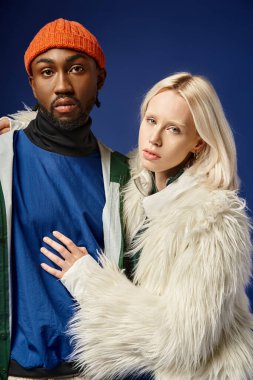 Kışın arka planda dağla poz veren çok ırklı çift, Afro-Amerikan erkek ve kadın.