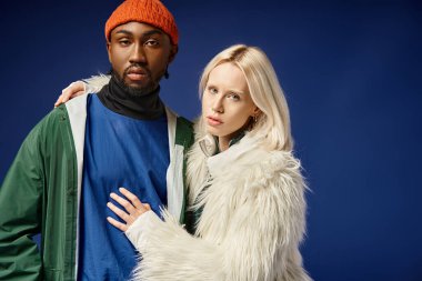 Kışın arka planda dağla poz veren çok ırklı çift, Afro-Amerikan erkek ve kadın.