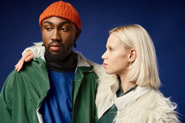 Kışın arka planda dağla poz veren çok ırklı çift, Afro-Amerikan erkek ve kadın.