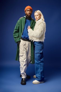 Kışın arka planda dağla poz veren çok ırklı çift, Afro-Amerikan erkek ve kadın.