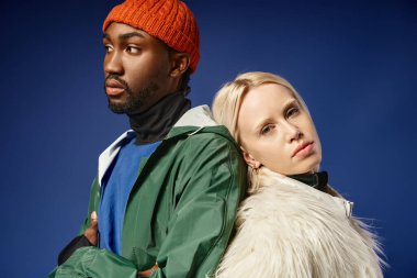 Kışın arka planda dağla poz veren çok ırklı çift, Afro-Amerikan erkek ve kadın.