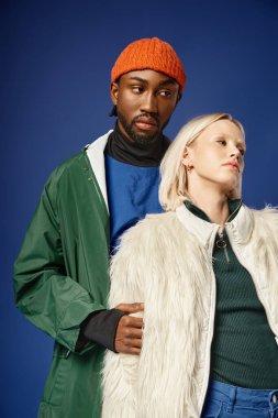 Kışın arka planda dağla poz veren çok ırklı çift, Afro-Amerikan erkek ve kadın.