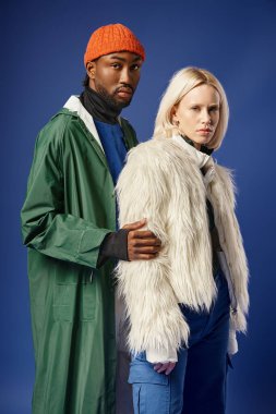 Kışın arka planda dağla poz veren çok ırklı çift, Afro-Amerikan erkek ve kadın.