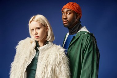 Kışın arka planda dağla poz veren çok ırklı çift, Afro-Amerikan erkek ve kadın.