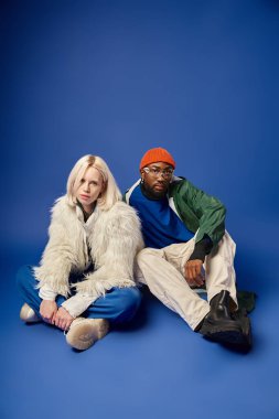 Kışın arka planda dağla poz veren çok ırklı çift, Afro-Amerikan erkek ve kadın.