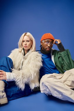 Kışın arka planda dağla poz veren çok ırklı çift, Afro-Amerikan erkek ve kadın.