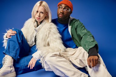 Kışın arka planda dağla poz veren çok ırklı çift, Afro-Amerikan erkek ve kadın.