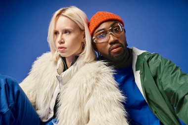 Kışın arka planda dağla poz veren çok ırklı çift, Afro-Amerikan erkek ve kadın.