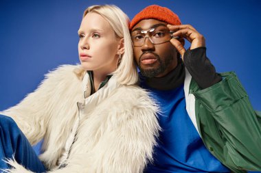 Kışın arka planda dağla poz veren çok ırklı çift, Afro-Amerikan erkek ve kadın.