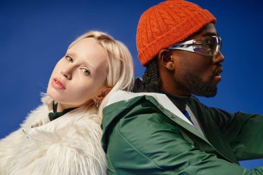 Kışın arka planda dağla poz veren çok ırklı çift, Afro-Amerikan erkek ve kadın.