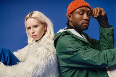 Kışın arka planda dağla poz veren çok ırklı çift, Afro-Amerikan erkek ve kadın.