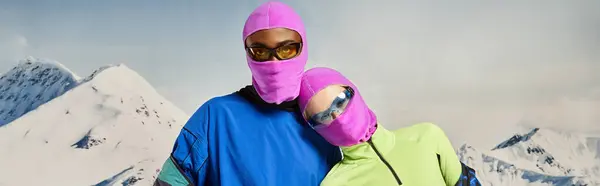 stock image young multiethnic couple in pink balaclavas and sunglasses hugging, winter concept, banner