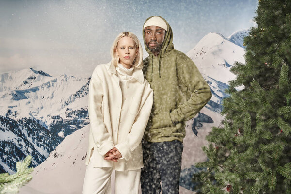 красивая стильная пара позирует вместе под снегопадом в модных теплых куртках, зимняя концепция