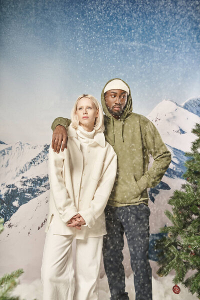 красивый мужчина в стильной куртке кладет руку на плечо своей девушки под снегопадом, зимой