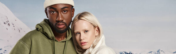 interracial couple posing together in warm jackets with snowy backdrop, winter fashion, banner