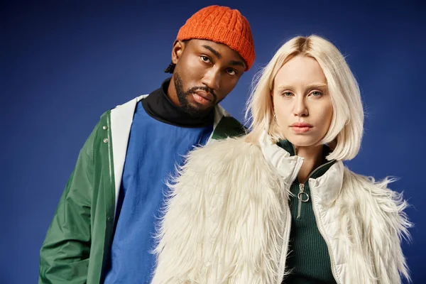 Kışın arka planda dağla poz veren çok ırklı çift, Afro-Amerikan erkek ve kadın.