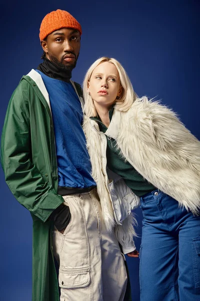 Kışın arka planda dağla poz veren çok ırklı çift, Afro-Amerikan erkek ve kadın.
