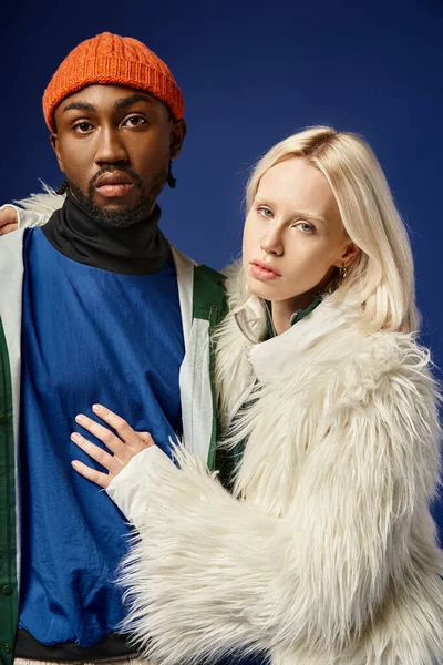 Kışın arka planda dağla poz veren çok ırklı çift, Afro-Amerikan erkek ve kadın.