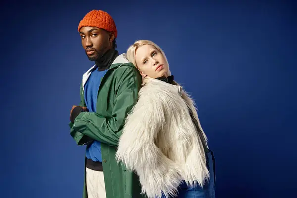 Stock image multiethnic couple posing in winter attire with mountain on backdrop, african american man and woman