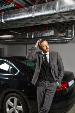handsome professional in elegant smart suit posing near his car on parking lot and looking away clipart