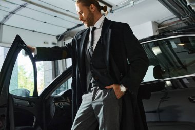 Arabasının yanında el ele poz veren şık ve şık giyinen çekici bir adam, iş konsepti.