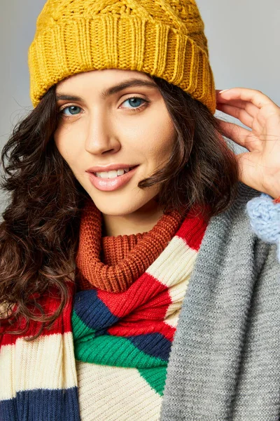 stock image portrait of happy woman with curly hair in bobble hat and cozy sweater with stripped scarf