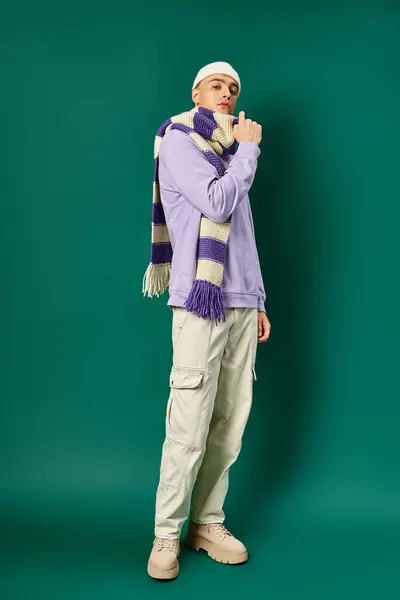紫色のスウェットシャツ 剥がれたスカーフ ターコイズの背景に立っているビーニーの帽子の良い見た目 — ストック写真