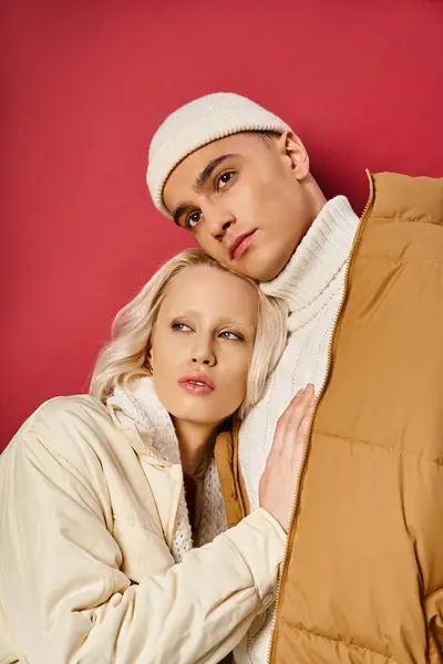 スタイリッシュなアウターウェアの若いロマンチックなカップルは抱擁し 赤い背景 冬のファッションを遠ざけます — ストック写真