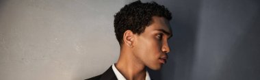 attractive young african american man with accessories in black suit posing and looking away, banner clipart