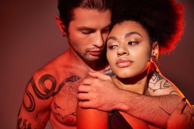 İyi görünümlü, dövmeli, Afrikalı Amerikalı sevgilisine sımsıkı sarılan, seksi bir çift.