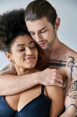 appealing young multicultural boyfriend and girlfriend in underwear hugging warmly, togetherness clipart