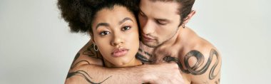 Genç adam güzel Afrikalı Amerikalı kız arkadaşına sarılıyor gri arka planda, seksi çift, afiş