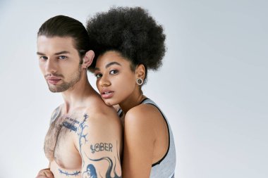 Güzel görünümlü Afro-Amerikan kadın dövmeli erkek arkadaşına arkadan sarılıyor, seksi çift.
