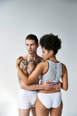 Çekici Afrikalı Amerikalı kadının, dövmeli genç erkek arkadaşına sarılışının arkası. Seksi bir çift.