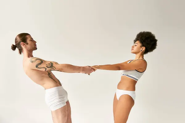 stock image young multiracial sexy couple in underwear holding hands and looking at each other sensually