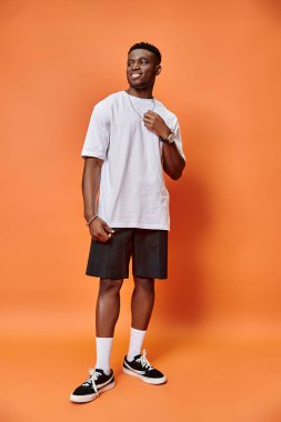 cheerful young african american man in street casual outfit on orange backdrop, fashion concept clipart