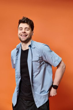happy attractive man in casual outfit on orange backdrop looking at camera, fashion concept clipart