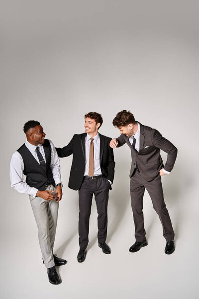 appealing jolly diverse friends in business casual outfits smiling happily on gray backdrop