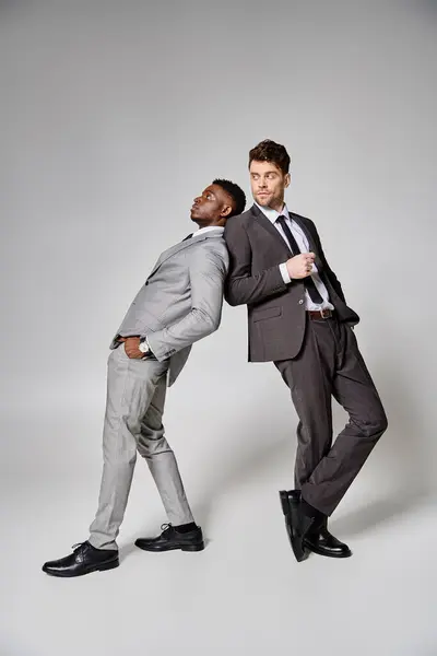 stock image two appealing stylish multicultural male models in business smart attires posing on gray backdrop